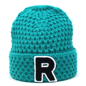 Nahaufnahme einer himmelblauen Strickmütze mit einem schwarz-weißen R-Buchstaben-Patch