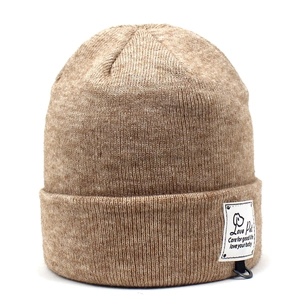 Detail of the brown knit beanie featuring a minimalist side woven label and thick texture