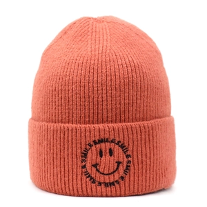 Detailed view of the orange ribbed knit beanie featuring a black smile embroidery