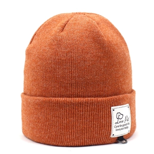 Detailed knit texture of orange sheep cashmere beanie with brand label and metal D-ring