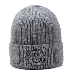 Macro detail of gray knitted beanie showing textured thick yarn and smile embroidery