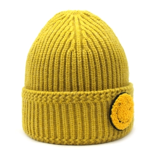 Détail du bonnet en maille côtelée jaune avec un écusson smiley en tissu bouclé