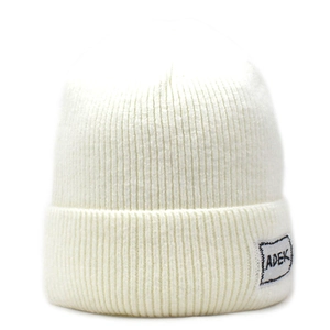 Dettaglio del berretto bianco in maglia a coste con toppa logo ADEK sul bordo risvoltato