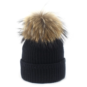 Detailed texture of black knit beanie with premium natural raccoon fur pompom detail
