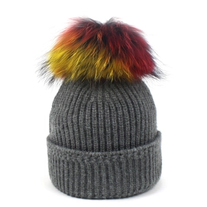 Dark grey knitted beanie with large colorful raccoon fur pompom and ribbed cuff