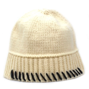 Close-up of knit beanie featuring creamy white fabric with black decorative seam details
