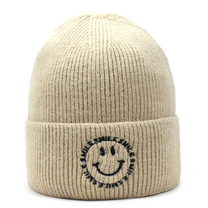 Close-up of the beige ribbed knit beanie featuring a black embroidered smile graphic