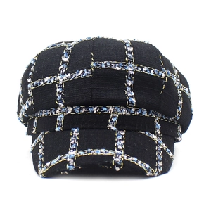 Close-up of black plaid newsboy hat with light blue and gold woven tweed fabric details