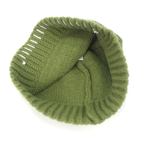 Inside view of a loose green knit beanie showing ribbed hem details and interior label
