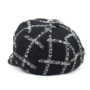 Close-up of black and blue wool tweed newsboy hat with golden metallic thread detail