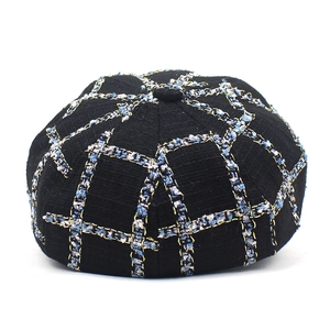 Detail of tweed newsboy cap with black and blue plaid pattern and gold thread texture
