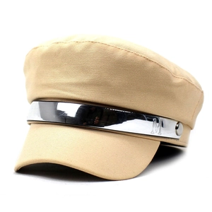 Détail de la casquette militaire beige avec sangle métallique argentée et gravure de la lettre M