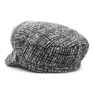 Détail de la casquette gavroche en tweed noir et blanc avec texture et boucle métal