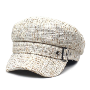 Détail d'une casquette gavroche en tweed blanc avec boucles métalliques argentées