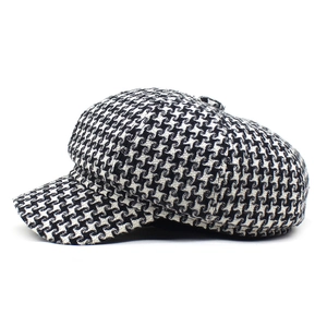 Close-up detail of the classic black and white houndstooth wool fabric texture on a newsboy cap