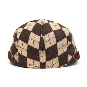 Detail of brown diamond check flat cap featuring vintage side leather straps and metal buckles