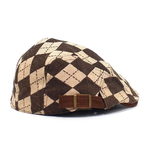 Detail of checkered flat cap with adjustable brown suede strap and metallic buckle