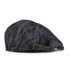 Detail of the vintage grey jacquard denim fabric and bronze metal buckle on the beret