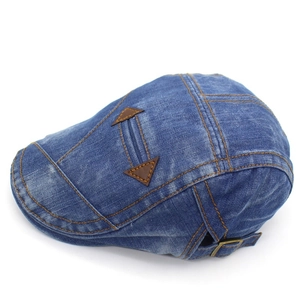 Detail of blue denim flat cap with adjustable metal buckle and leather patches