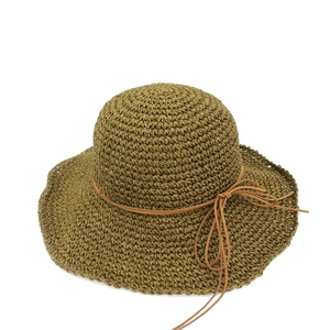 Detailed close-up of dark green raffia sun hat with woven texture and leather bow