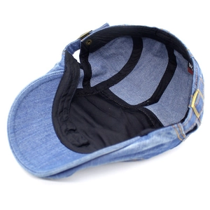 Detail view of denim beret featuring adjustable gold buckle and black inner lining