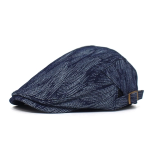 Detail of the navy denim flat cap with adjustable copper buckle and woven texture