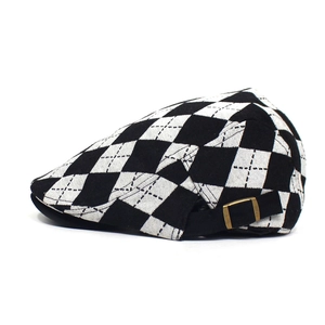 Close-up of the vintage black and white checkered newsboy cap with metal buckle