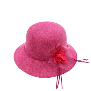 Détail de la texture d'un chapeau de soleil rose en paille avec grande fleur rouge