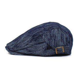 Detail of blue denim flat cap with adjustable bronze metal buckle and twill texture