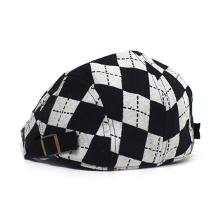 Detail of the vintage black and white argyle beret hat with a bronze metal buckle