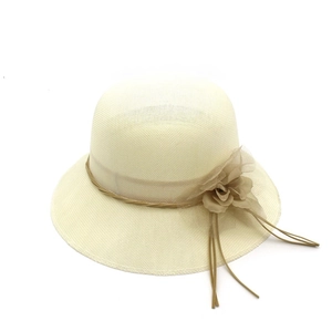 Détail d'un chapeau de paille crème avec fleur en tissu et ruban tressé élégant