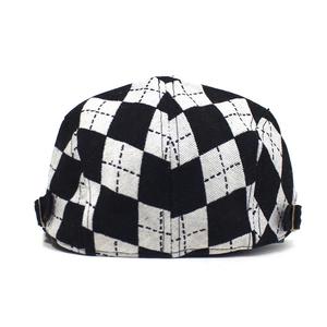 Detail view of the checkerboard beret showing the textured tweed fabric and metal buckle