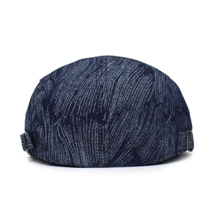 Detailed view of dark blue denim flat cap featuring textured weave and metal side buckle