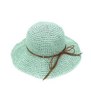 Detailed close-up of woven straw texture and leather ribbon bow on mint green sun hat