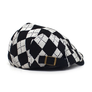 Detail of black and white argyle pattern and bronze metal buckle on newsboy cap