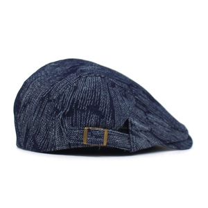 Detail view of denim beret featuring vintage bronze metal buckle and woven strap
