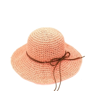 Detailed texture of peach raffia sun hat with wide brim and dark brown ribbon bow