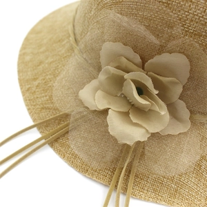 Détail de chapeau de soleil en paille kaki avec fleur en gaze et perles élégantes