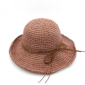 Macro shot of hand-woven brick red raffia sun hat texture with elegant bow detail