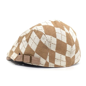 Detail view of brown argyle pattern fabric and adjustable metal buckle on a flat cap