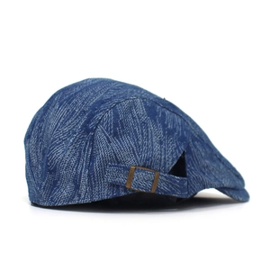 Detail of adjustable metal buckle and denim texture on the retro blue flat cap