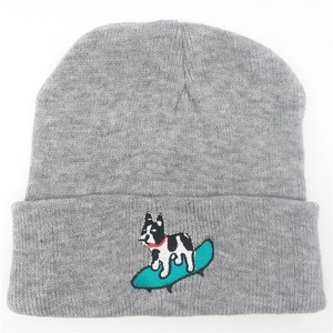 Close-up of embroidered puppy on surfboard on grey knitted winter beanie hat