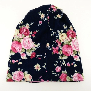 Detailed close-up of dark blue floral knitted beanie with pink rose pattern