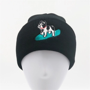 Close-up of a black knit beanie featuring detailed embroidery of a French bulldog on a surfboard