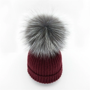 Detail der weinroten Strickmütze mit einem hochwertigen, übergroßen Pelzbommel aus Silberfuchs