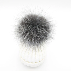 Detailed close-up of white ribbed knit beanie with a fluffy grey faux fur pom pom