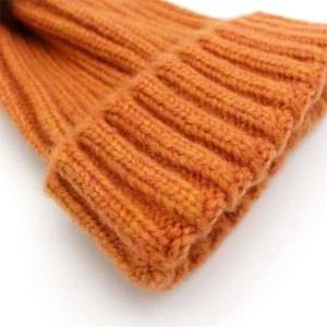 Detailed close-up of orange knitted beanie featuring thick ribbed texture and warm yarn fabric