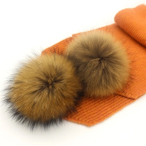 Detailed knit texture and fluffy faux fur pompom on vibrant orange winter scarf