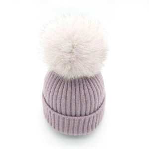 Winter knitted beanie in lavender purple with a large fluffy pompom on white background