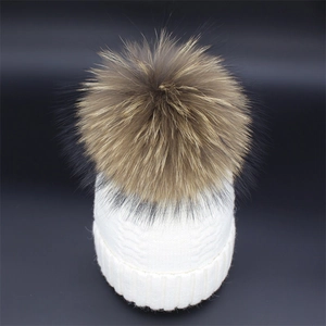 Close-up of knit texture and 15cm raccoon fur pompom on cream winter beanie hat